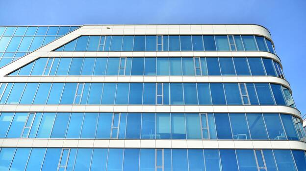 Glass building with transparent facade of the building and blue sky. Structural glass wall reflecting blue sky. Abstract modern architecture fragment. Contemporary architectural background. photo