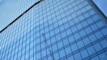 Glass building with transparent facade of the building and blue sky. Structural glass wall reflecting blue sky. Abstract modern architecture fragment. Contemporary architectural background. photo