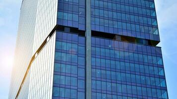 Glass building with transparent facade of the building and blue sky. Structural glass wall reflecting blue sky. Abstract modern architecture fragment. Contemporary architectural background. photo