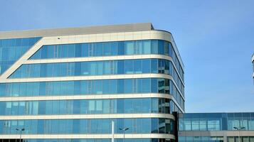 Glass building with transparent facade of the building and blue sky. Structural glass wall reflecting blue sky. Abstract modern architecture fragment. Contemporary architectural background. photo