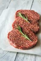 Raw beef patties on the white parchment photo