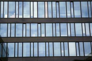 Glass building with transparent facade of the building and blue sky. Structural glass wall reflecting blue sky. Abstract modern architecture fragment. Contemporary architectural background. photo