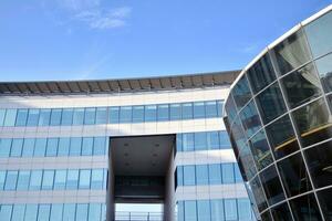 Glass building with transparent facade of the building and blue sky. Structural glass wall reflecting blue sky. Abstract modern architecture fragment. Contemporary architectural background. photo