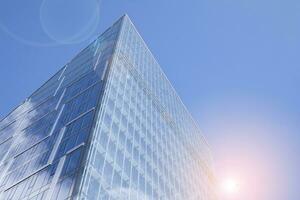 Glass building with transparent facade of the building and blue sky. Structural glass wall reflecting blue sky. Abstract modern architecture fragment. Contemporary architectural background. photo