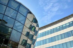 Glass building with transparent facade of the building and blue sky. Structural glass wall reflecting blue sky. Abstract modern architecture fragment. Contemporary architectural background. photo