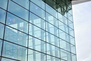 Modern office building with glass facade on a clear sky background. Transparent glass wall of office building. photo