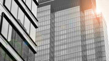 Glass modern building with blue sky background. View and architecture details. Urban abstract - windows of glass office building in  sunlight day. Black and white. photo