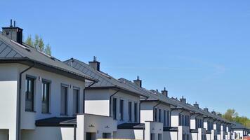 Suburban neighborhood with condominium complex. Suburban area with modern geometric family houses. Row of family houses against blue sky. photo