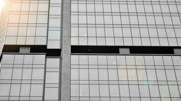 Glass modern building with blue sky background. View and architecture details. Urban abstract - windows of glass office building in  sunlight day. Black and white. photo