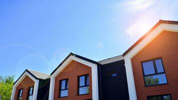 Suburban neighborhood with condominium complex. Suburban area with modern geometric family houses. Row of family houses against blue sky. photo