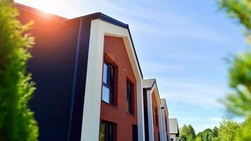 Suburban neighborhood with condominium complex. Suburban area with modern geometric family houses. Row of family houses against blue sky. photo