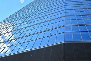 Modern office building with glass facade on a clear sky background. Transparent glass wall of office building. photo