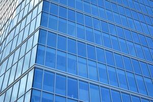 Modern office building with glass facade on a clear sky background. Transparent glass wall of office building. photo