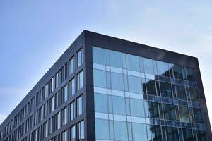 Modern office building with glass facade on a clear sky background. Transparent glass wall of office building. photo