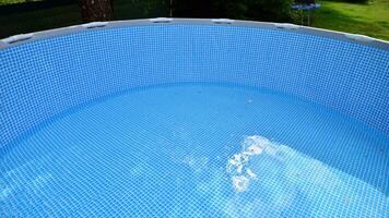 Swimming pool with metal frame for home and garden. Frame swimming pool in the yard. Garden in the background. Summer holiday fun and recreation. photo