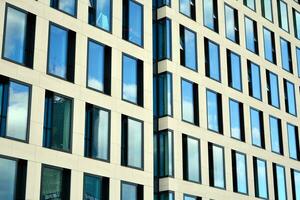 Modern office building with glass facade on a clear sky background. Transparent glass wall of office building. photo