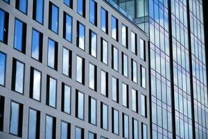 Modern office building with glass facade on a clear sky background. Transparent glass wall of office building. photo