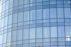 moderno oficina edificio con vaso fachada en un claro cielo antecedentes. transparente vaso pared de oficina edificio. foto