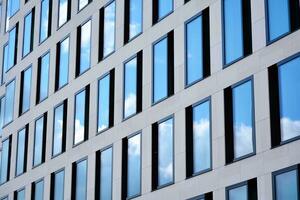 Modern office building with glass facade on a clear sky background. Transparent glass wall of office building. photo