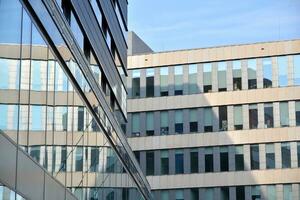 Modern office building with glass facade on a clear sky background. Transparent glass wall of office building. photo