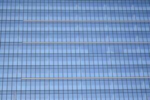 Modern office building with glass facade on a clear sky background. Transparent glass wall of office building. photo