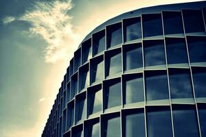 moderno oficina edificio con vaso fachada en un claro cielo antecedentes. transparente vaso pared de oficina edificio. foto