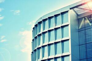 Modern office building with glass facade on a clear sky background. Transparent glass wall of office building. photo