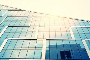 Modern office building with glass facade on a clear sky background. Transparent glass wall of office building. photo