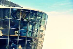 Modern office building with glass facade on a clear sky background. Transparent glass wall of office building. photo