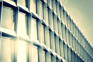 Modern office building with glass facade on a clear sky background. Transparent glass wall of office building. photo