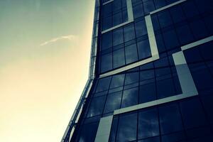 Modern office building with glass facade on a clear sky background. Transparent glass wall of office building. photo