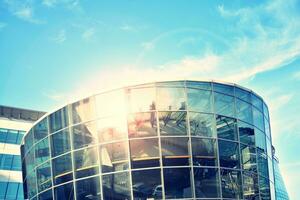 Modern office building with glass facade on a clear sky background. Transparent glass wall of office building. photo