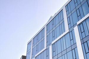 Glass building with transparent facade of the building and blue sky. Structural glass wall reflecting blue sky. Abstract modern architecture fragment. Contemporary architectural background. photo