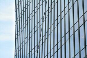 Glass building with transparent facade of the building and blue sky. Structural glass wall reflecting blue sky. Abstract modern architecture fragment. Contemporary architectural background. photo