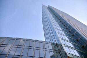 Glass building with transparent facade of the building and blue sky. Structural glass wall reflecting blue sky. Abstract modern architecture fragment. Contemporary architectural background. photo