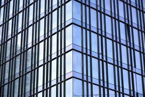 Glass building with transparent facade of the building and blue sky. Structural glass wall reflecting blue sky. Abstract modern architecture fragment. Contemporary architectural background. photo