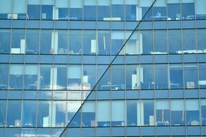 Glass building with transparent facade of the building and blue sky. Structural glass wall reflecting blue sky. Abstract modern architecture fragment. Contemporary architectural background. photo