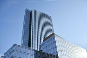 Glass building with transparent facade of the building and blue sky. Structural glass wall reflecting blue sky. Abstract modern architecture fragment. Contemporary architectural background. photo