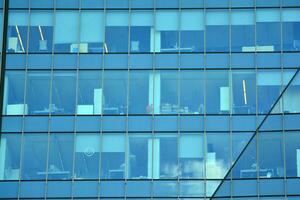 Glass building with transparent facade of the building and blue sky. Structural glass wall reflecting blue sky. Abstract modern architecture fragment. Contemporary architectural background. photo