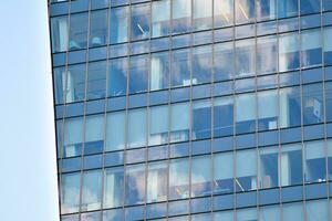 Glass building with transparent facade of the building and blue sky. Structural glass wall reflecting blue sky. Abstract modern architecture fragment. Contemporary architectural background. photo