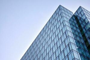 Glass building with transparent facade of the building and blue sky. Structural glass wall reflecting blue sky. Abstract modern architecture fragment. Contemporary architectural background. photo