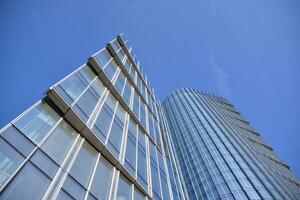 Glass building with transparent facade of the building and blue sky. Structural glass wall reflecting blue sky. Abstract modern architecture fragment. Contemporary architectural background. photo