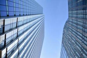Glass building with transparent facade of the building and blue sky. Structural glass wall reflecting blue sky. Abstract modern architecture fragment. Contemporary architectural background. photo
