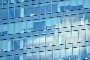 Glass building with transparent facade of the building and blue sky. Structural glass wall reflecting blue sky. Abstract modern architecture fragment. Contemporary architectural background. photo