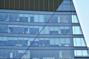 Glass building with transparent facade of the building and blue sky. Structural glass wall reflecting blue sky. Abstract modern architecture fragment. Contemporary architectural background. photo