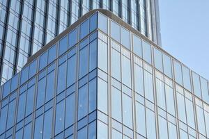 Glass building with transparent facade of the building and blue sky. Structural glass wall reflecting blue sky. Abstract modern architecture fragment. Contemporary architectural background. photo