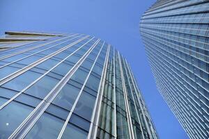 Glass building with transparent facade of the building and blue sky. Structural glass wall reflecting blue sky. Abstract modern architecture fragment. Contemporary architectural background. photo