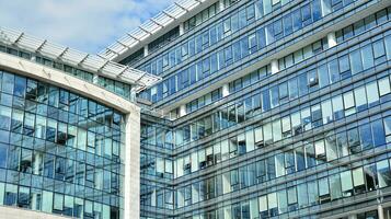 Glass building with transparent facade of the building and blue sky. Structural glass wall reflecting blue sky. Abstract modern architecture fragment. Contemporary architectural background. photo