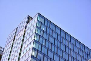 Glass building with transparent facade of the building and blue sky. Structural glass wall reflecting blue sky. Abstract modern architecture fragment. Contemporary architectural background. photo