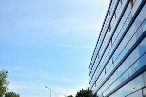 Glass building with transparent facade of the building and blue sky. Structural glass wall reflecting blue sky. Abstract modern architecture fragment. Contemporary architectural background. photo
